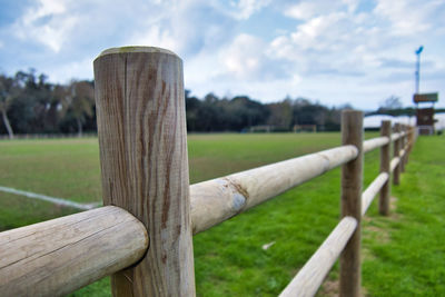 Close-up of wooden fence on field against sky