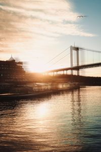 Bridge over river in city at sunset