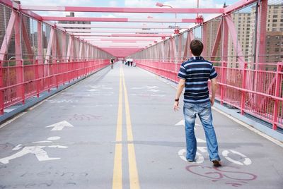 Rear view of man walking on footpath in city