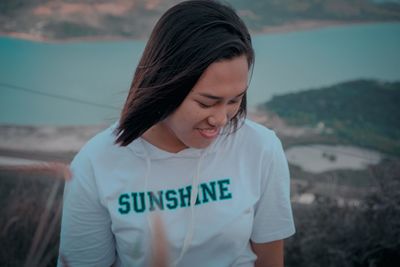 Close-up of smiling young woman standing against blurred background