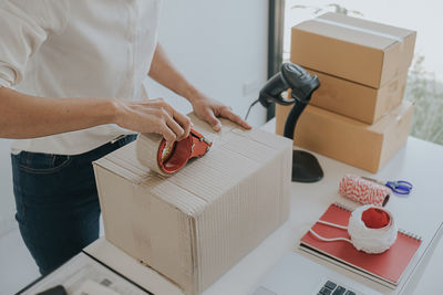 Midsection of woman holding box at table