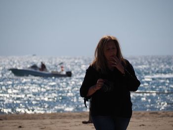 Mid adult man standing at beach against clear sky