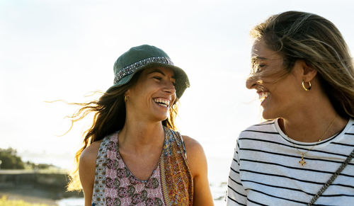 Cheerful young women against bright sky enjoying weekend together