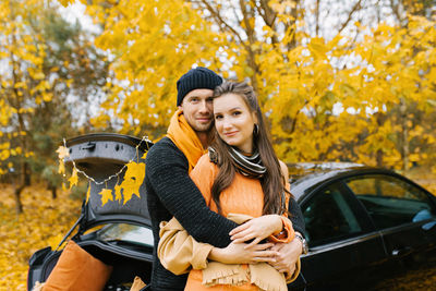 A young couple in love embraces in the autumn forest, walking and enjoying nature