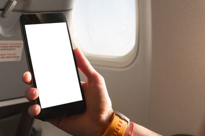 Midsection of man using mobile phone in airplane
