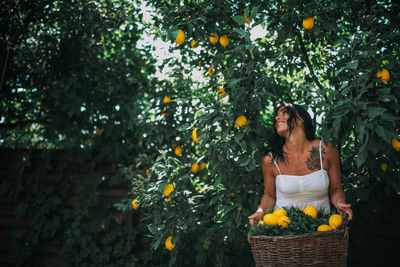 Woman standing by tree in basket