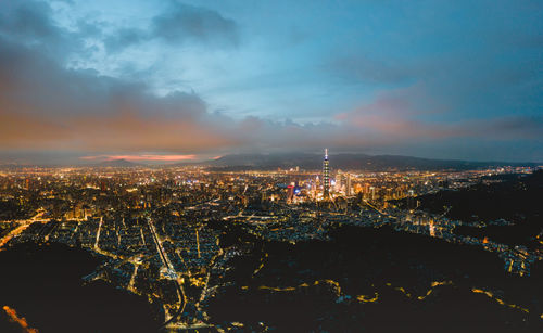 Aerial view of illuminated buildings against sky at night