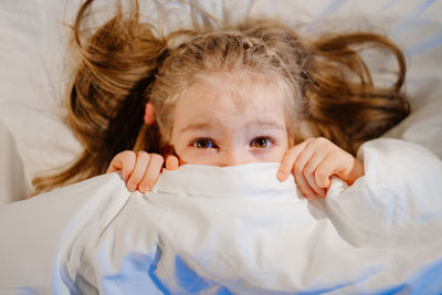 Portrait of cute girl lying on bed at home