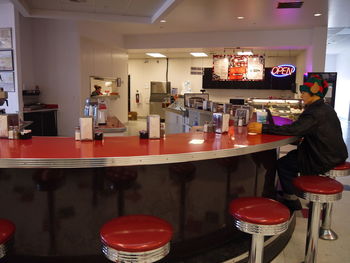 Man sitting on red stool at counter at cafe