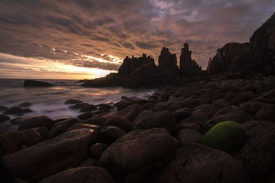 Rocks on beach against sky during sunset