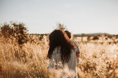 Rear view of woman standing on field against sky