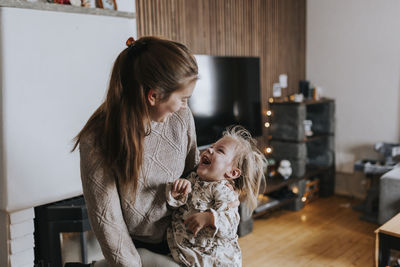 Smiling mother sitting with disabled child in living room