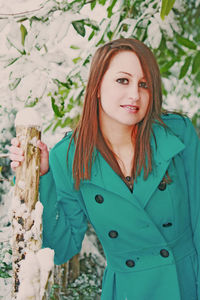 Portrait of a beautiful young woman standing against plants