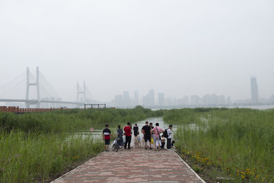 Rear view of people walking on bridge in city