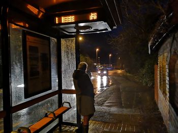 Rear view of man walking on street at night