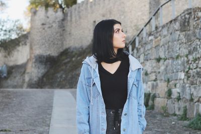 Young woman looking away against wall