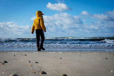 Full length of man standing on beach against sky