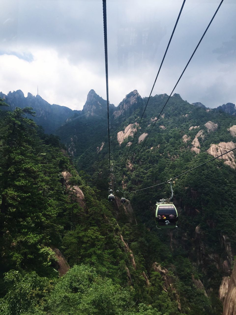 mountain, sky, tree, mountain range, cloud - sky, tranquility, landscape, overhead cable car, scenics, green color, tranquil scene, nature, power line, beauty in nature, cloud, lush foliage, growth, day, cable, non-urban scene, outdoors, plant, no people, cloudy, idyllic, hill, green, travel destinations, remote