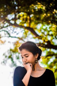 Young woman standing against tree