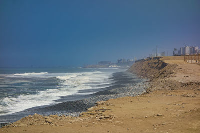 Scenic view of beach against clear blue sky