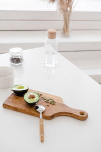 A still life sliced avocado with pumpkin seeds lies on a wooden board on a white table