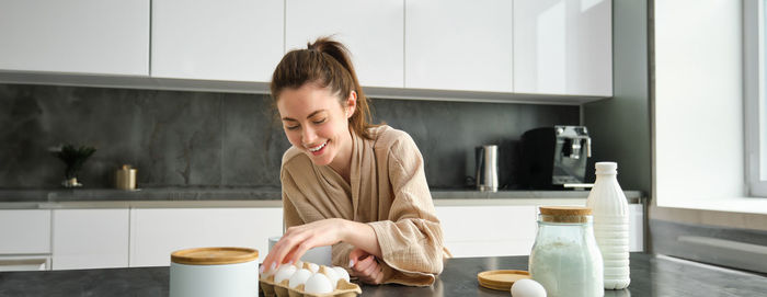 Side view of young woman preparing food in kitchen