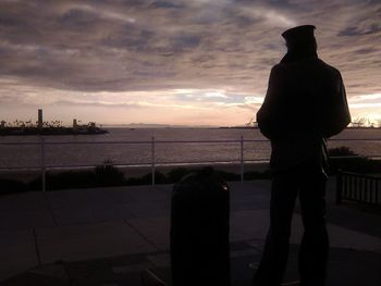 Silhouette man looking at sea against sky during sunset