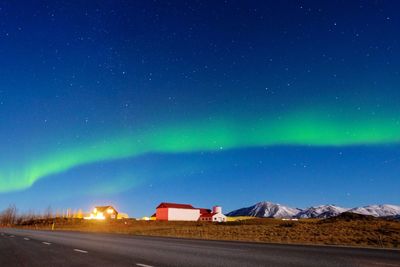 Northern lights above houses and mountain view.