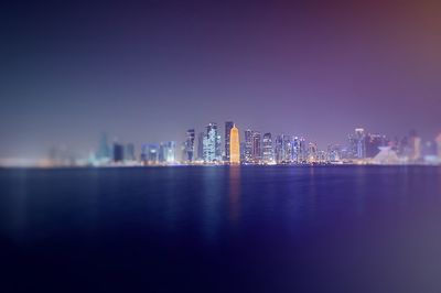 Illuminated buildings by river at night