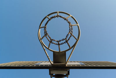 Directly below shot of metallic basketball hoop against clear blue sky