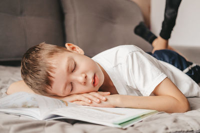 Portrait of a boy who fell asleep during homework lying on the couch. teenager over a notebook