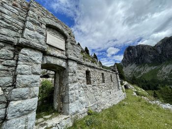 Low angle view of old ruin building against cloudy sky