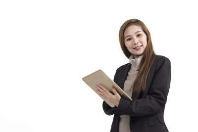 Portrait of young woman holding camera against white background