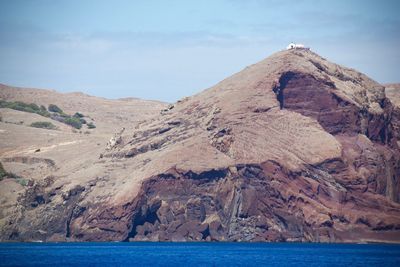 Scenic view of sea and mountain against cloudy sky