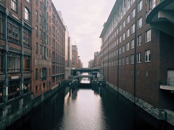 Canal amidst buildings against clear sky in city