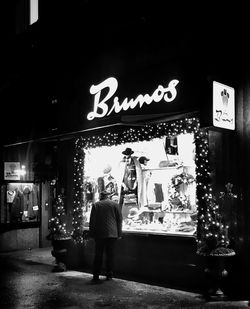 Man standing by illuminated sign at night