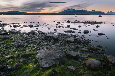 Rocks by sea against sky during sunset