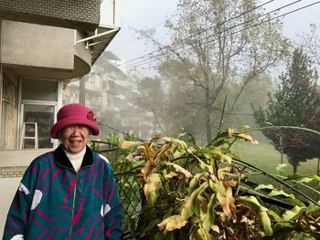 Senior woman standing by plants during foggy weather