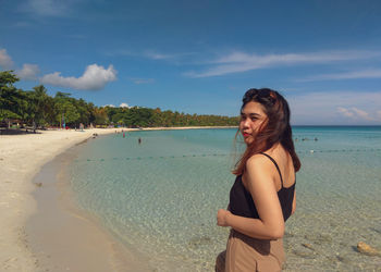 Side view of smiling young woman standing on beach