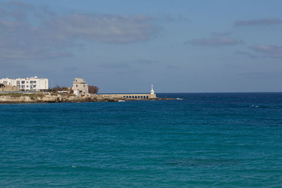 Scenic view of sea by buildings against sky