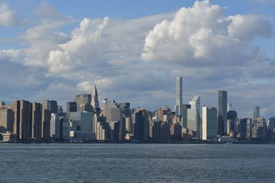 Sea by modern buildings against sky in city