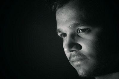 Close-up portrait of young man against black background