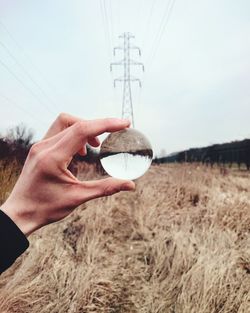 Close-up of man holding hands against sky