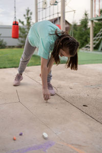 Girl draws with colorful crayons on pavement. children's drawings with chalk on wall. creative kid. 