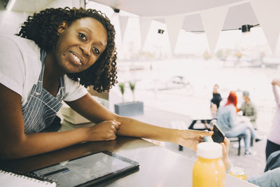Portrait of smiling young female food truck owner leaning on counter