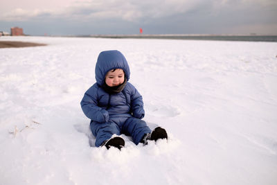 Cute baby boy in snow on an empty beach