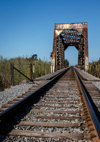 Railroad tracks and bridge against blue sky
