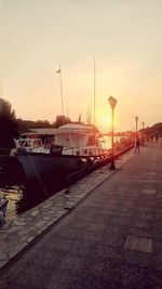 Boats moored at harbor during sunset