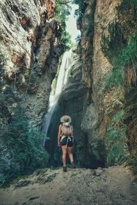 Full length of woman standing against waterfall