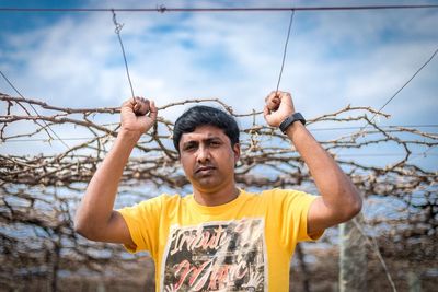 Portrait of young man standing against sky